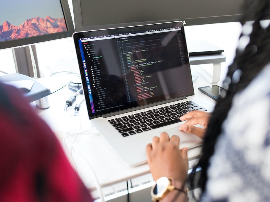 A Macbook screen with code, as seen from over the developer's shoulder